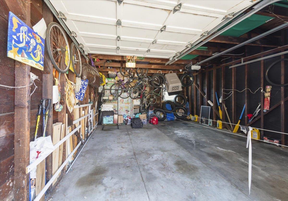 Open garage with exposed framing, bicycles, tires, and tools stored along the walls.