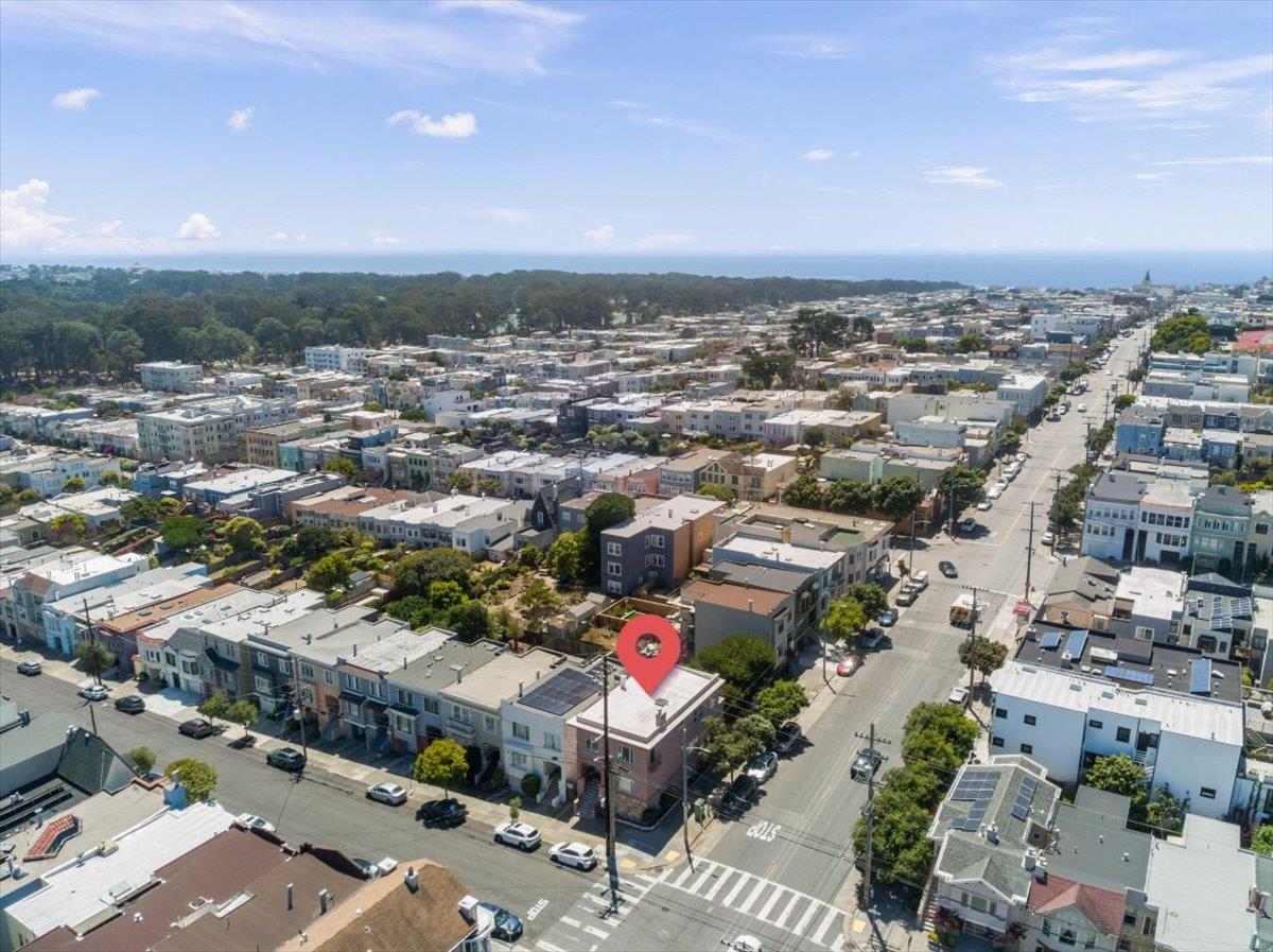 Aerial view of a red-pinned property among San Francisco rooftops, with ocean on the horizon.
