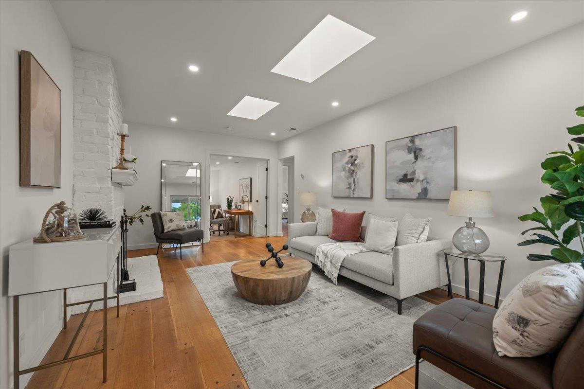 Living room with a white sofa, round wood coffee table, and white-painted brick fireplace wall.