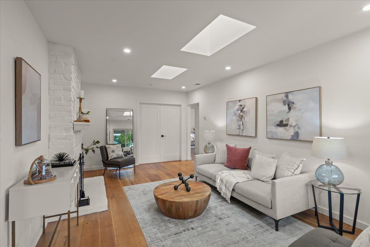 Living room with a white sofa, round wood coffee table, brick fireplace, and ceiling skylights.