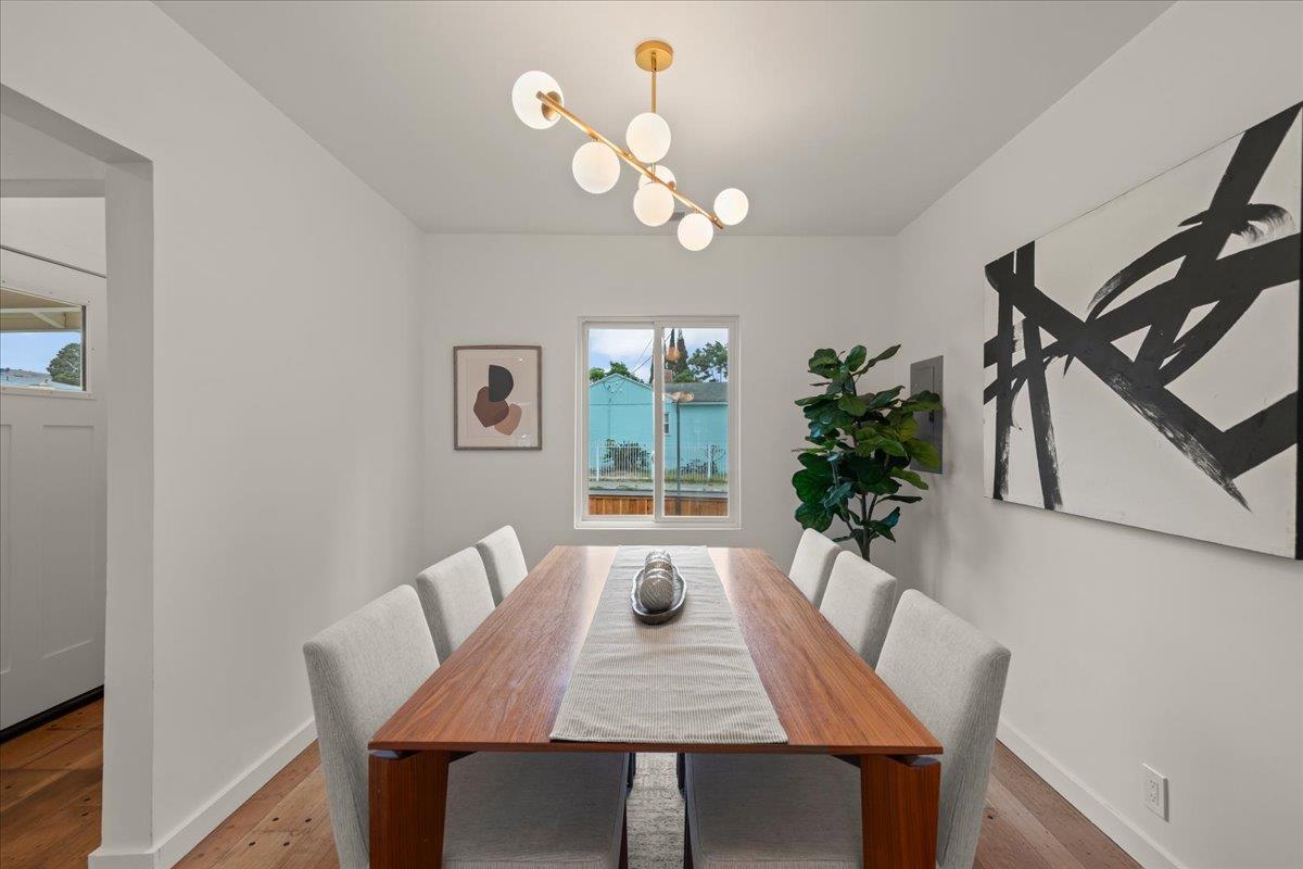 Dining room with a long wooden table, globe chandelier, abstract art, and hardwood floors.