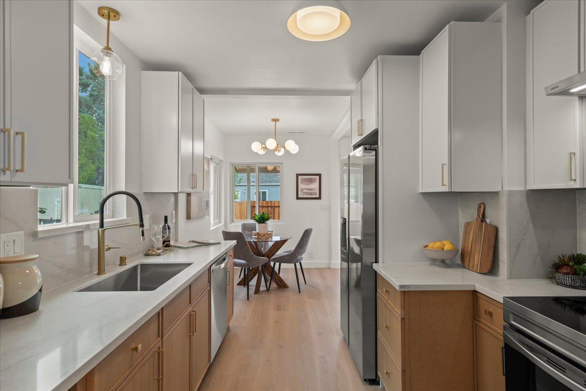 Renovated kitchen with white cabinets, wood lower cabinets, and a dining nook beyond the counter.