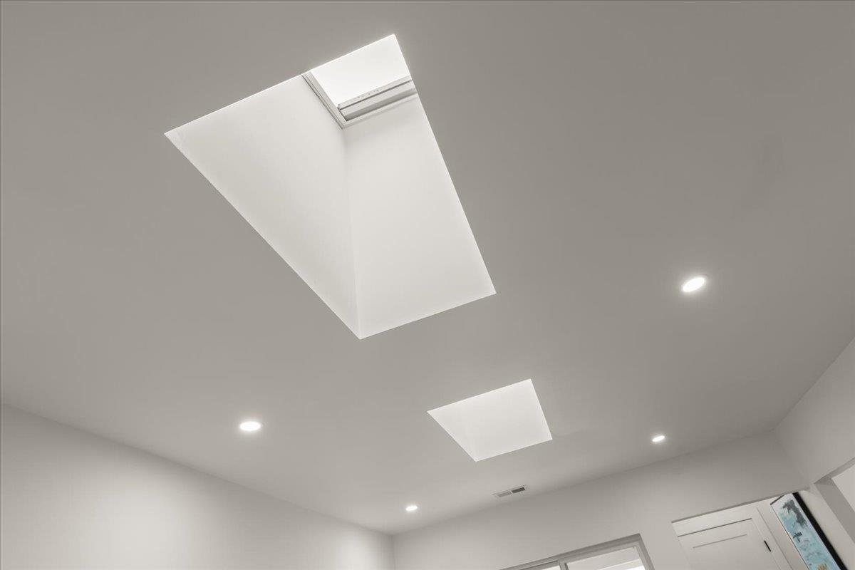 White ceiling with two skylights and recessed lights.