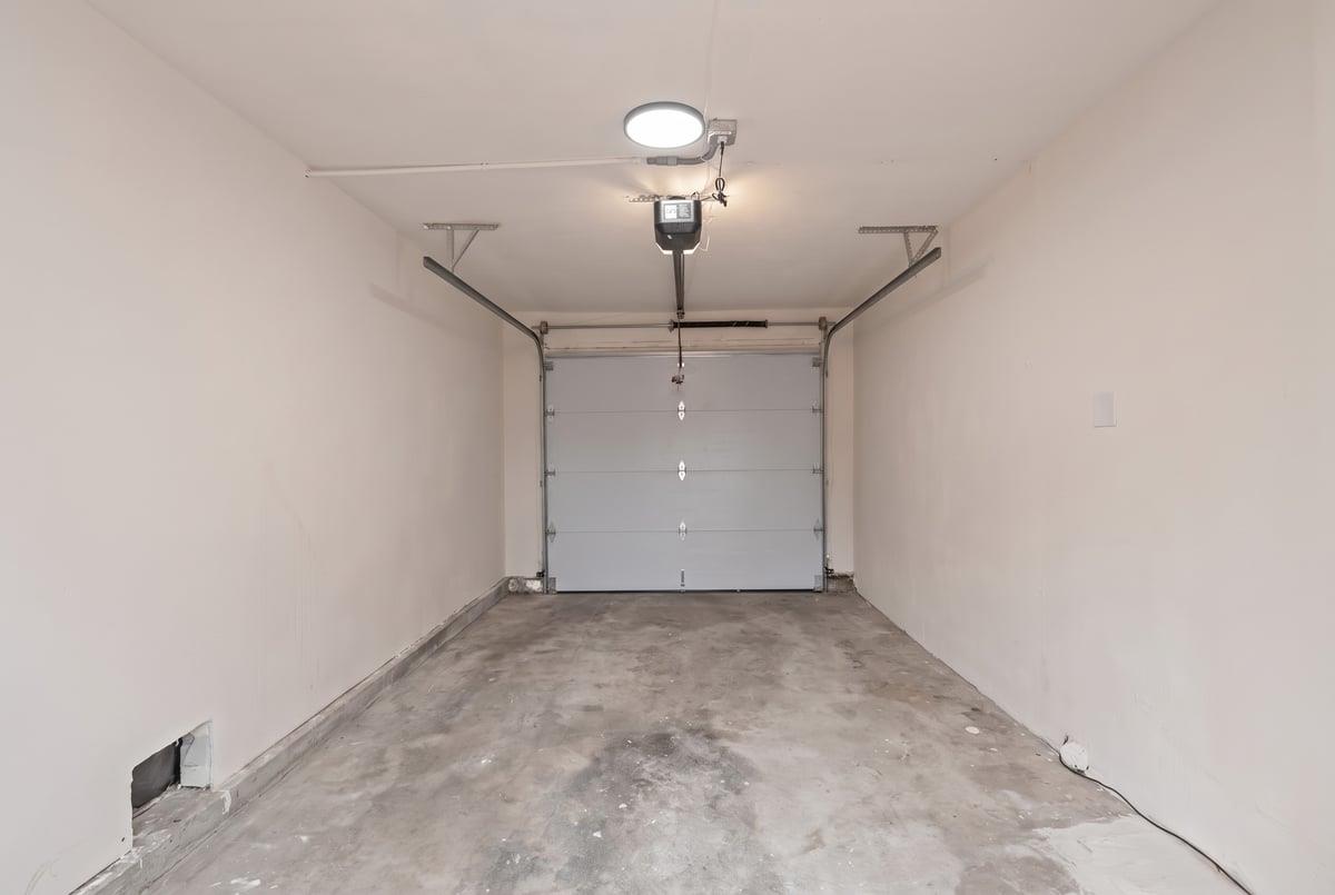 Empty garage with a concrete floor and closed sectional door.