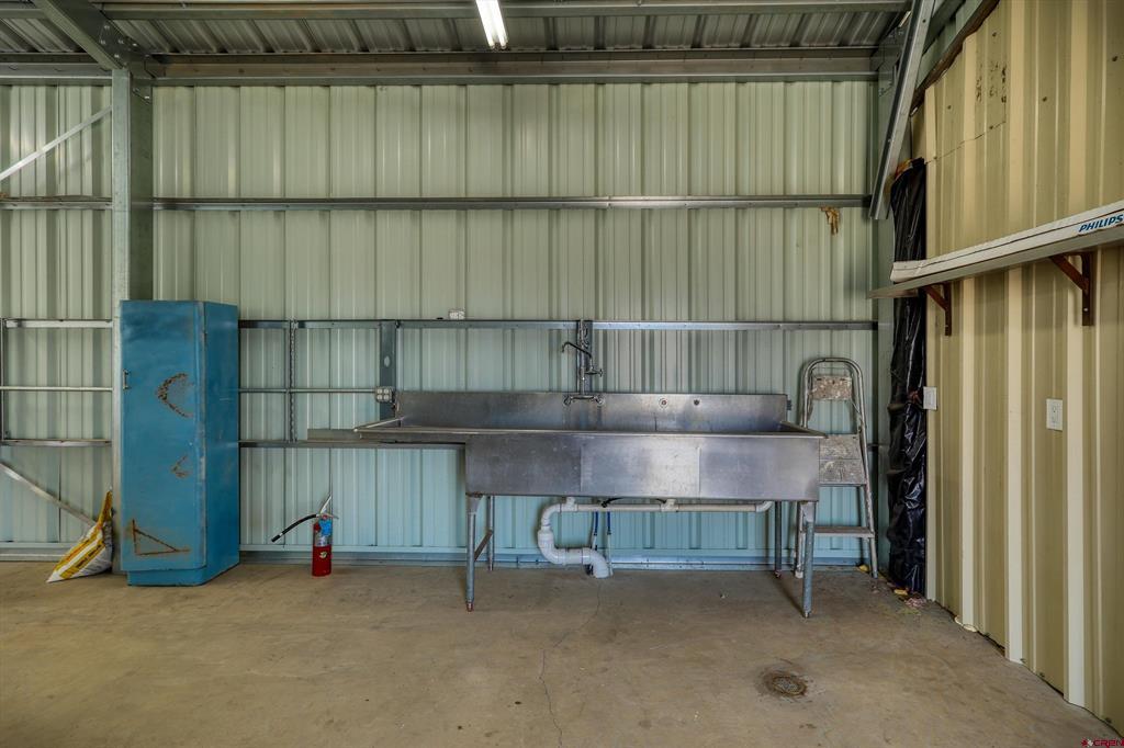 Metal-sided workshop with a large stainless utility sink and blue cabinet.
