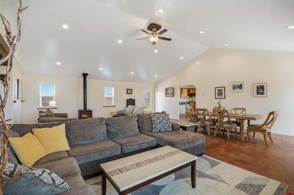 Open-plan living and dining room with a gray sectional and freestanding wood stove.