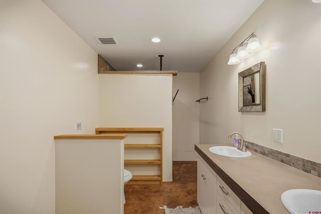 Bathroom with a long double-sink vanity and open wooden shelving.