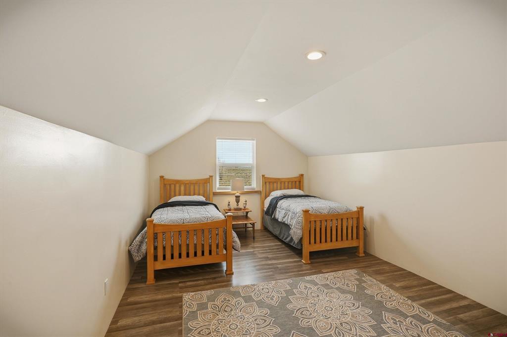 Upstairs bedroom with two wooden twin beds beneath a sloped ceiling.