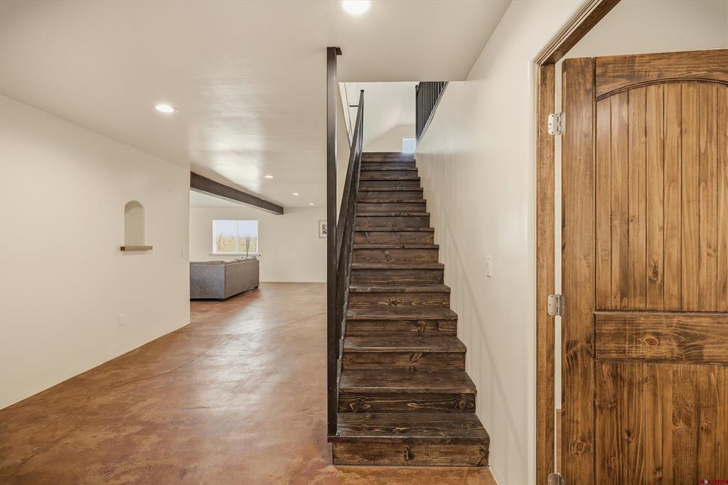 Home entry with a dark rustic wood staircase, matching front door, and open living area.