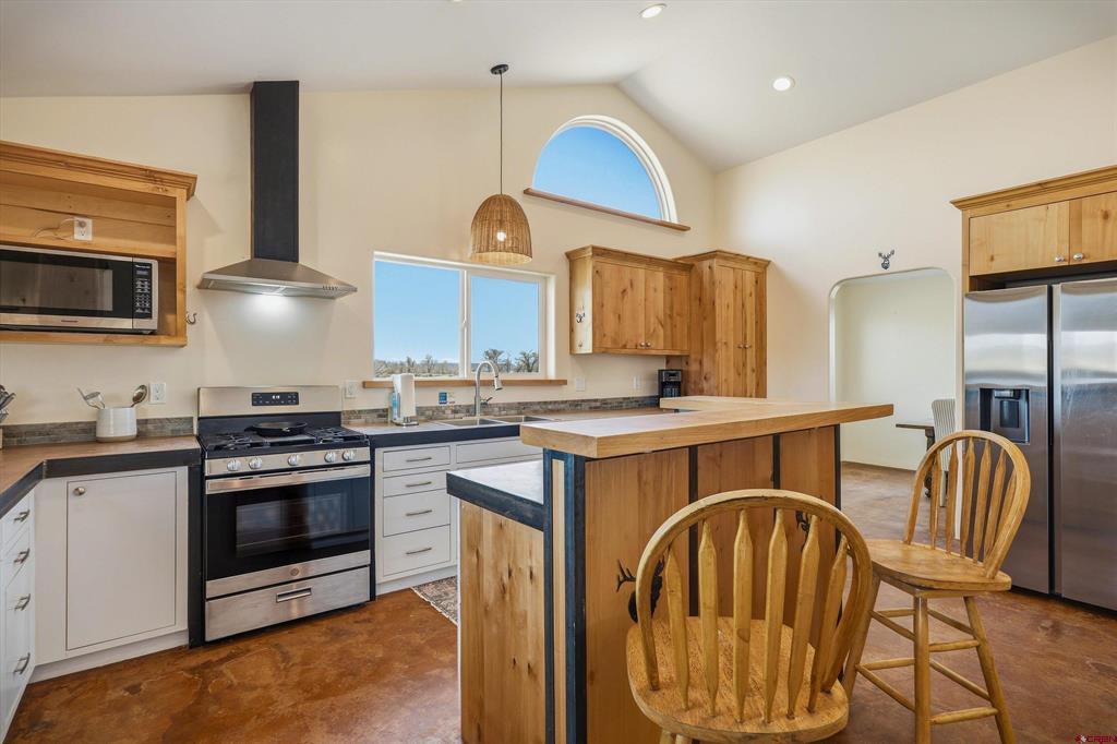 Kitchen with a large wood-paneled island, stainless steel appliances, and arched windows.