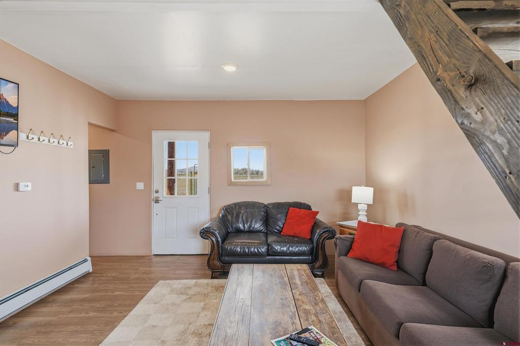 Living room with a leather loveseat, gray sofa, red cushions, and a prominent exposed timber beam.