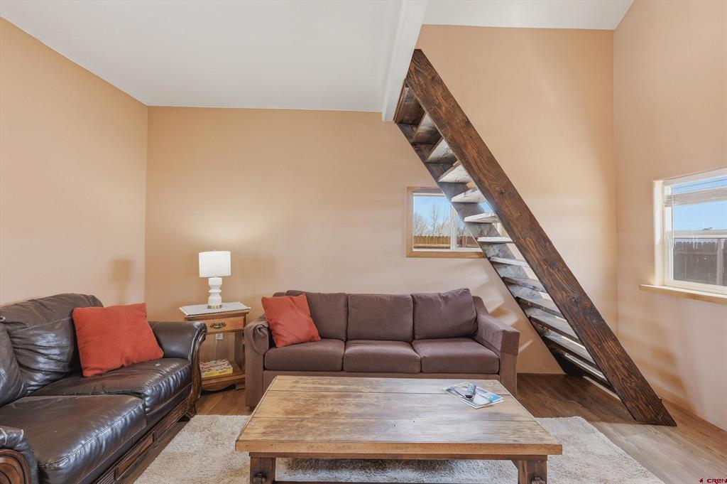 Living room with sofas and a rustic ladder-style staircase to a loft.