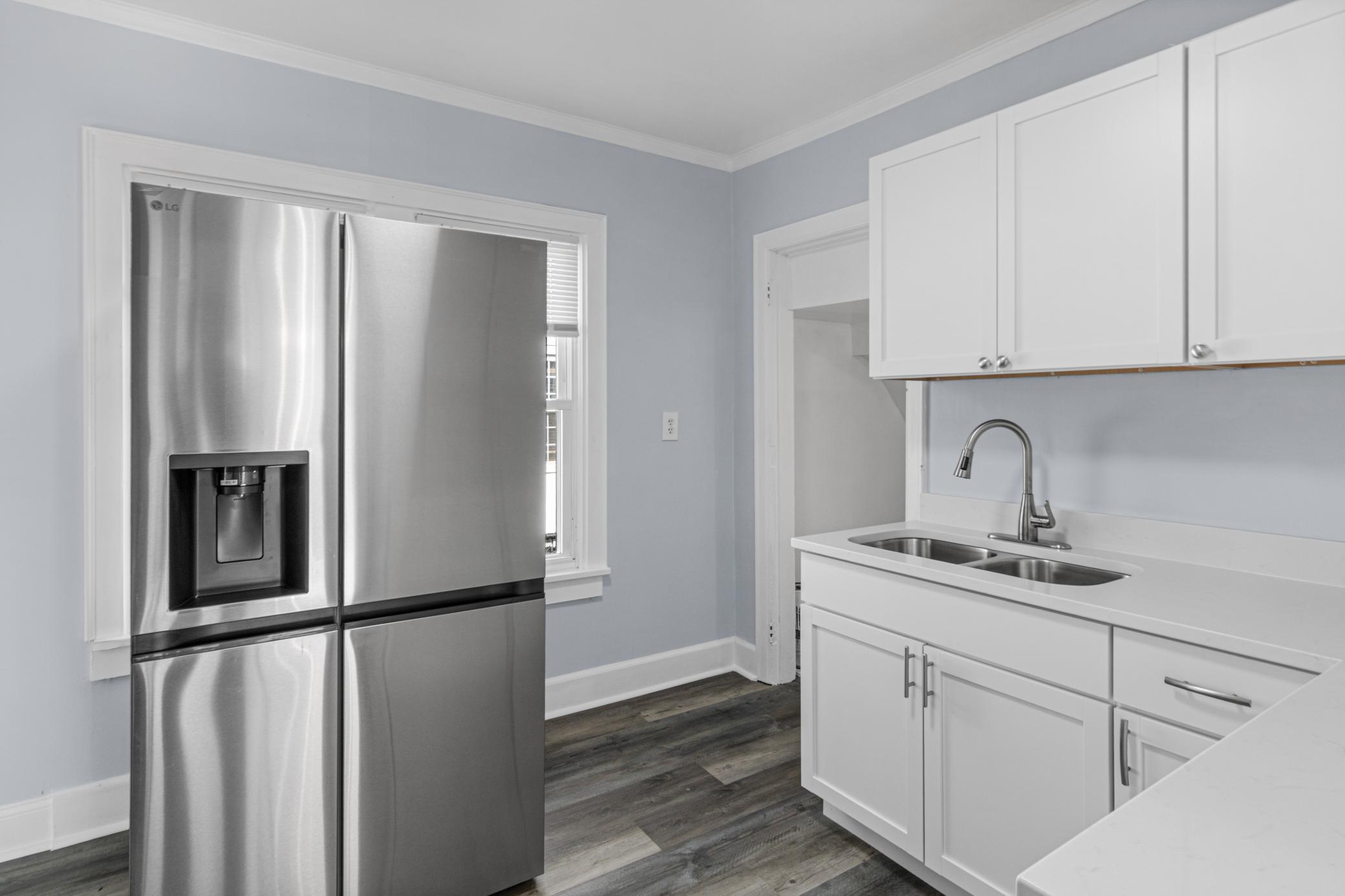 Kitchen with white cabinets, double-basin sink, and stainless steel refrigerator.