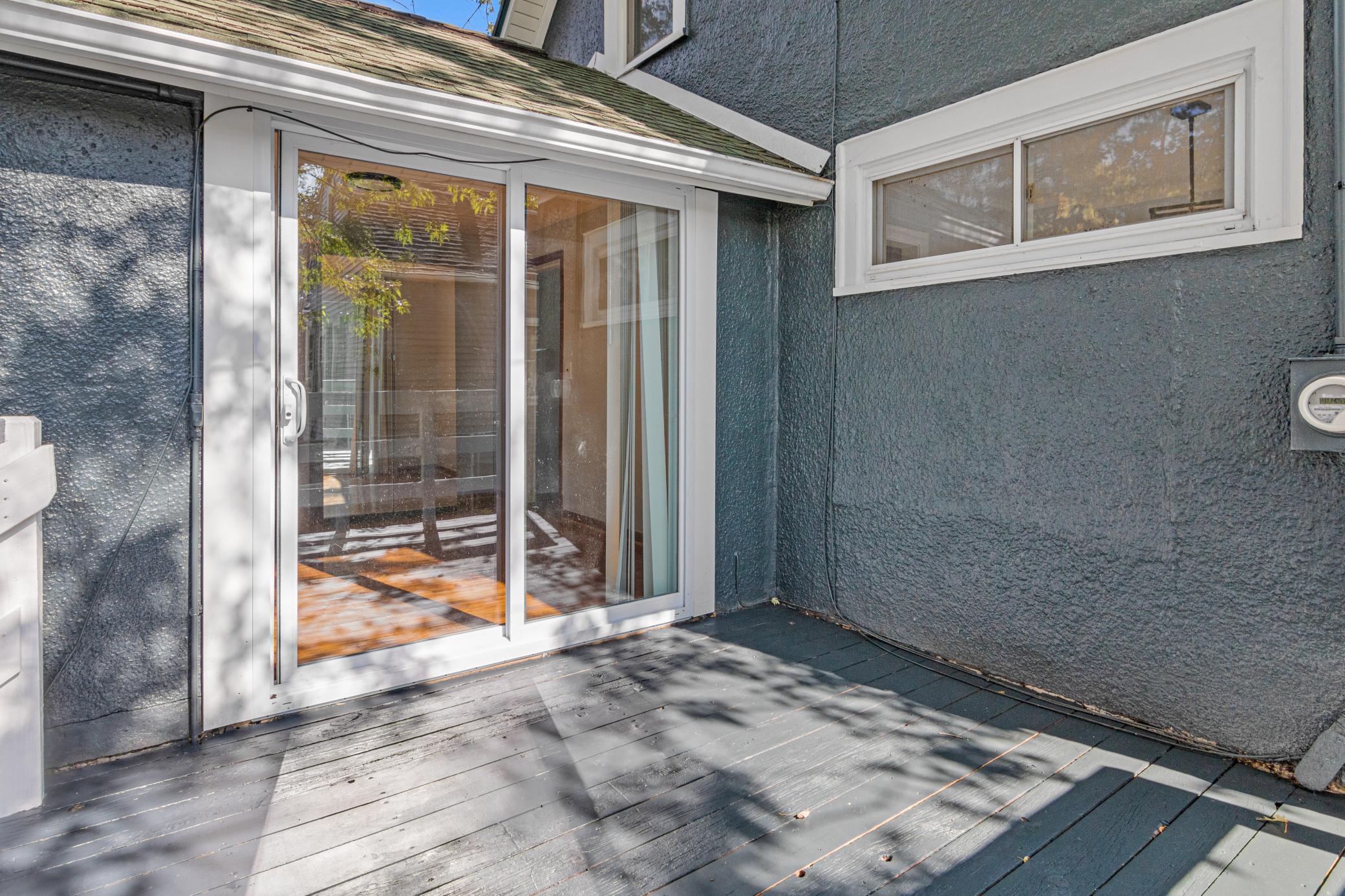 Gray deck beside a sliding glass door, with blue-gray siding and a high horizontal window.