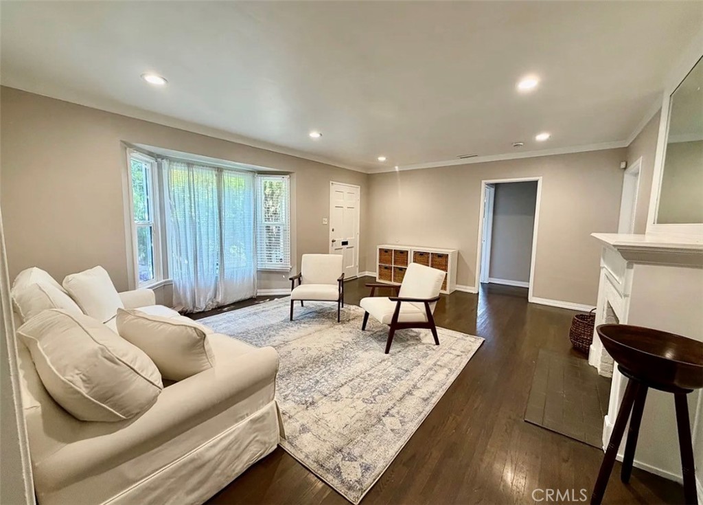 Living room with a cream sofa, two chairs, patterned rug, and bay window.