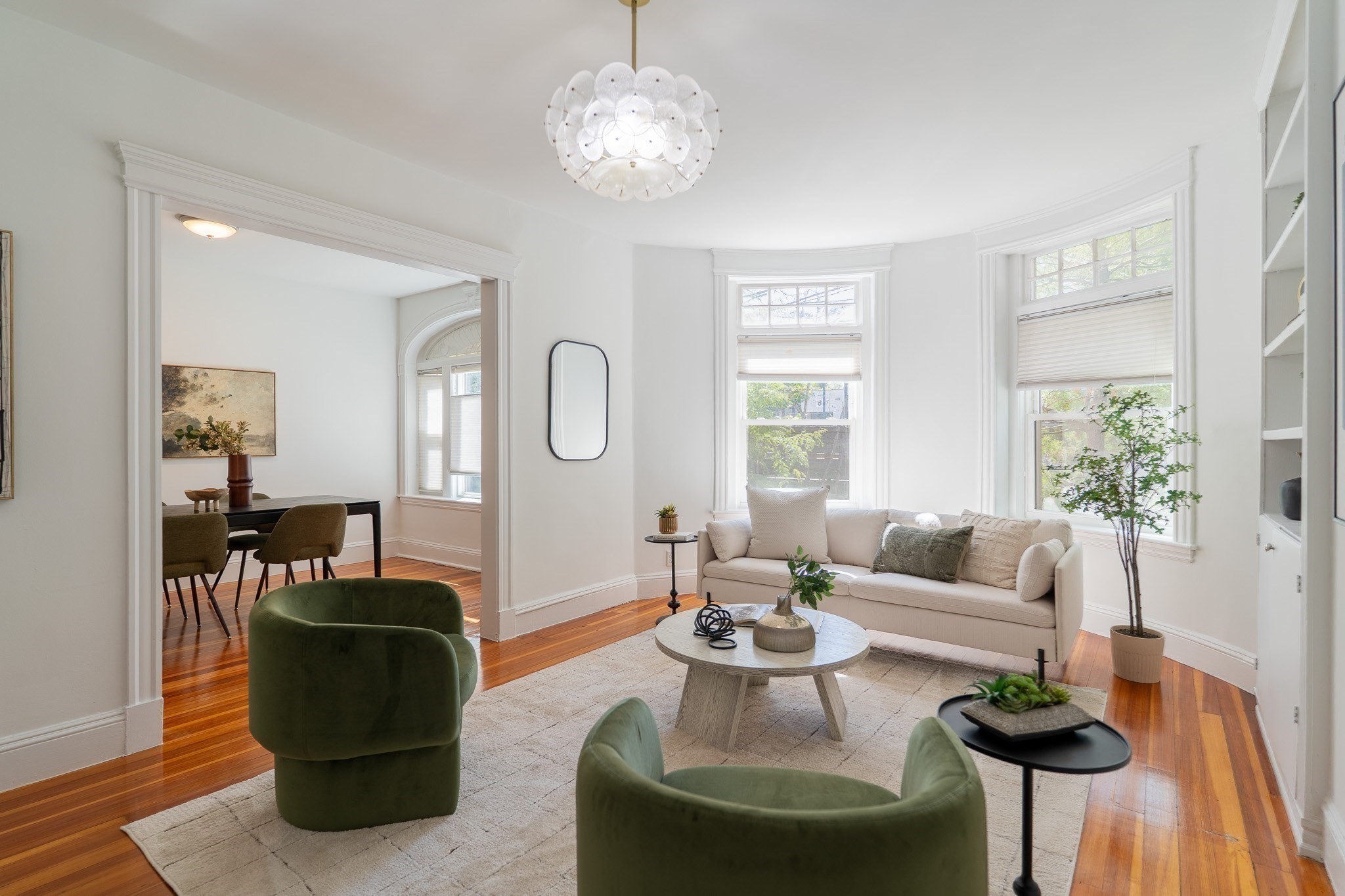 Staged living room with bay windows, hardwood floors, and adjoining dining area.