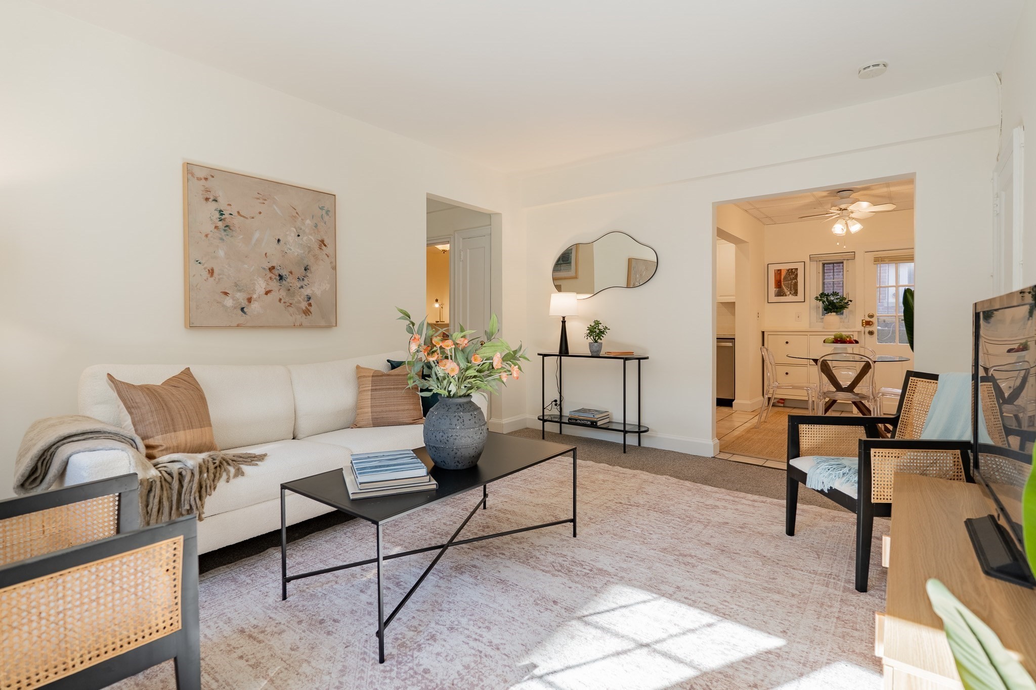 Staged living room with a white sofa, abstract artwork, and a doorway to the dining area.