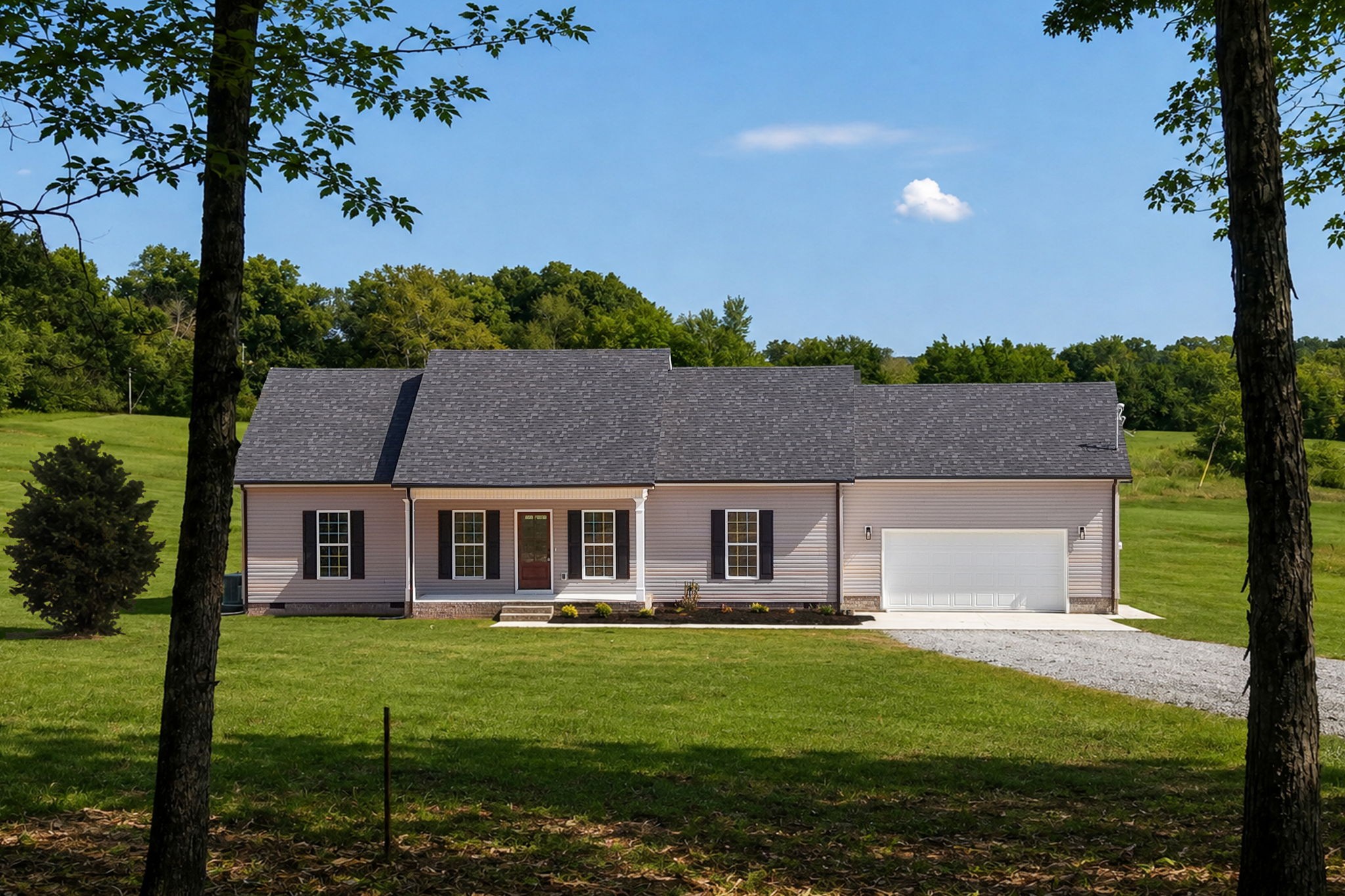 Single-story gray house with a white garage door on a tree-framed lawn.