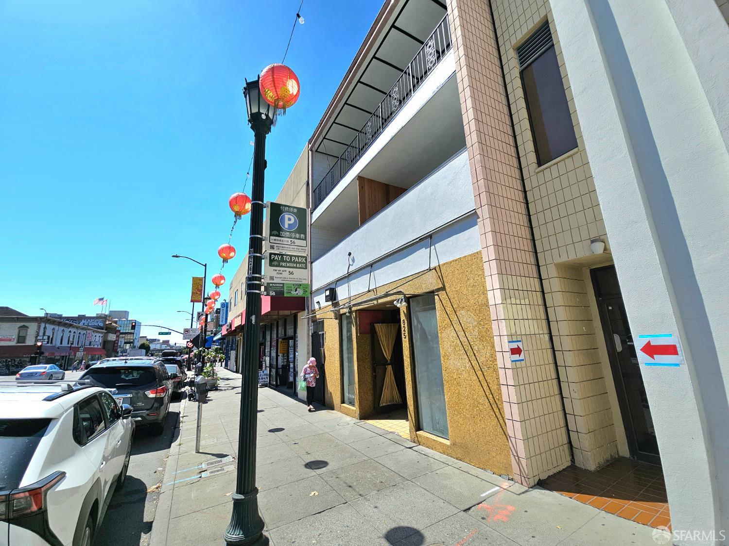 Urban building with a yellow-tiled storefront, upper balconies, and red lanterns along the sidewalk.