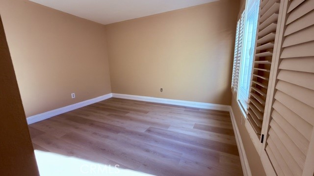 Empty room with light wood flooring and a shuttered window.