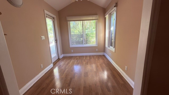 Vacant room with hardwood floors and windows on three sides.