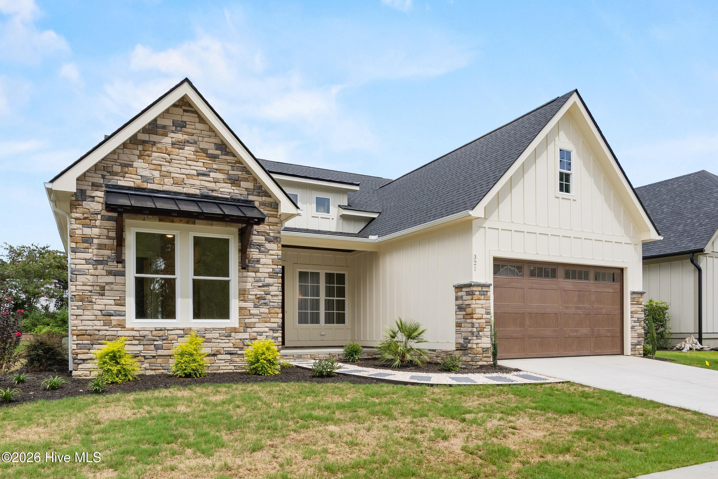 Home exterior with a stone-faced gable, white siding, and wooden garage door.