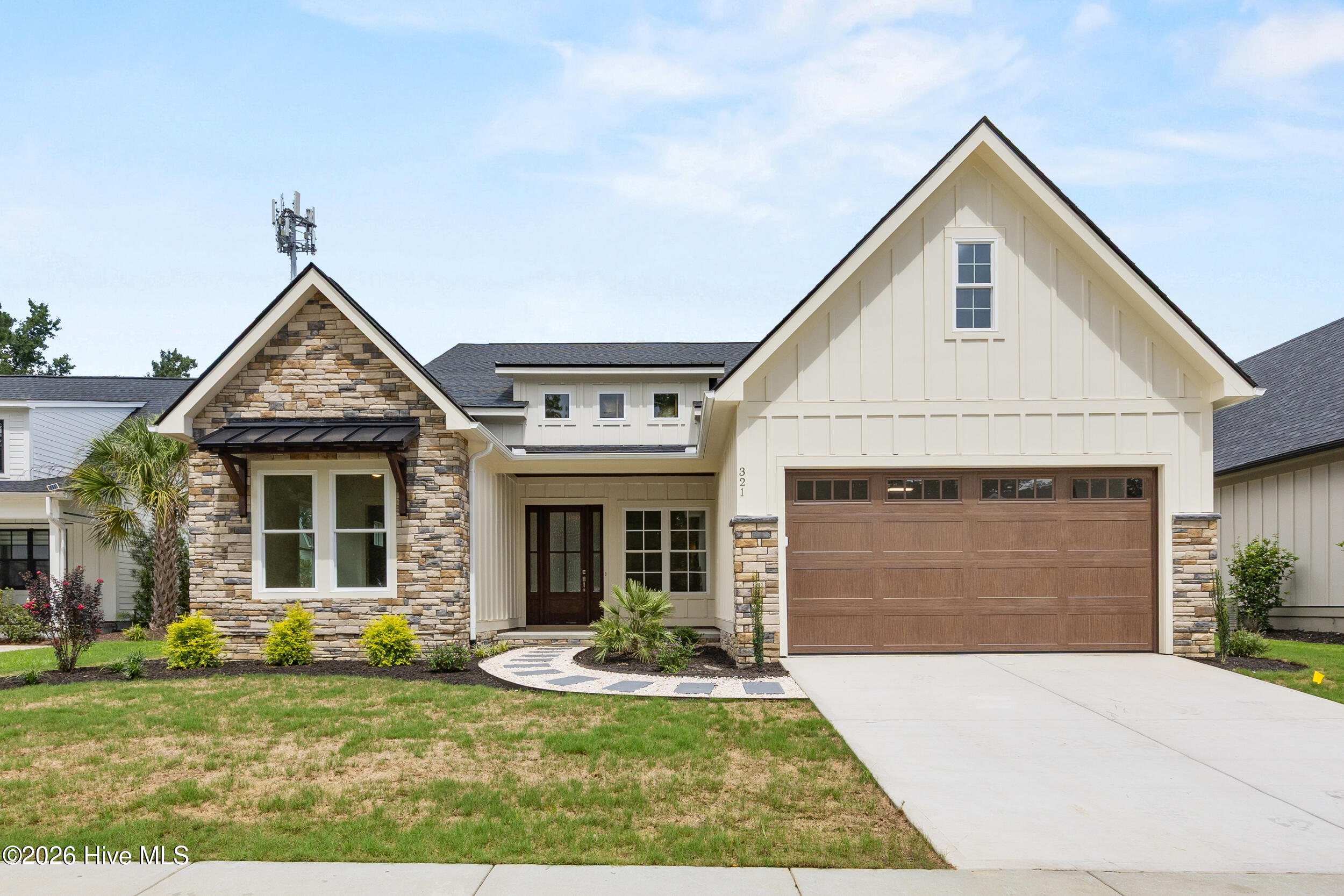 House exterior with a stone-faced gable, brown garage door, and landscaped front yard.