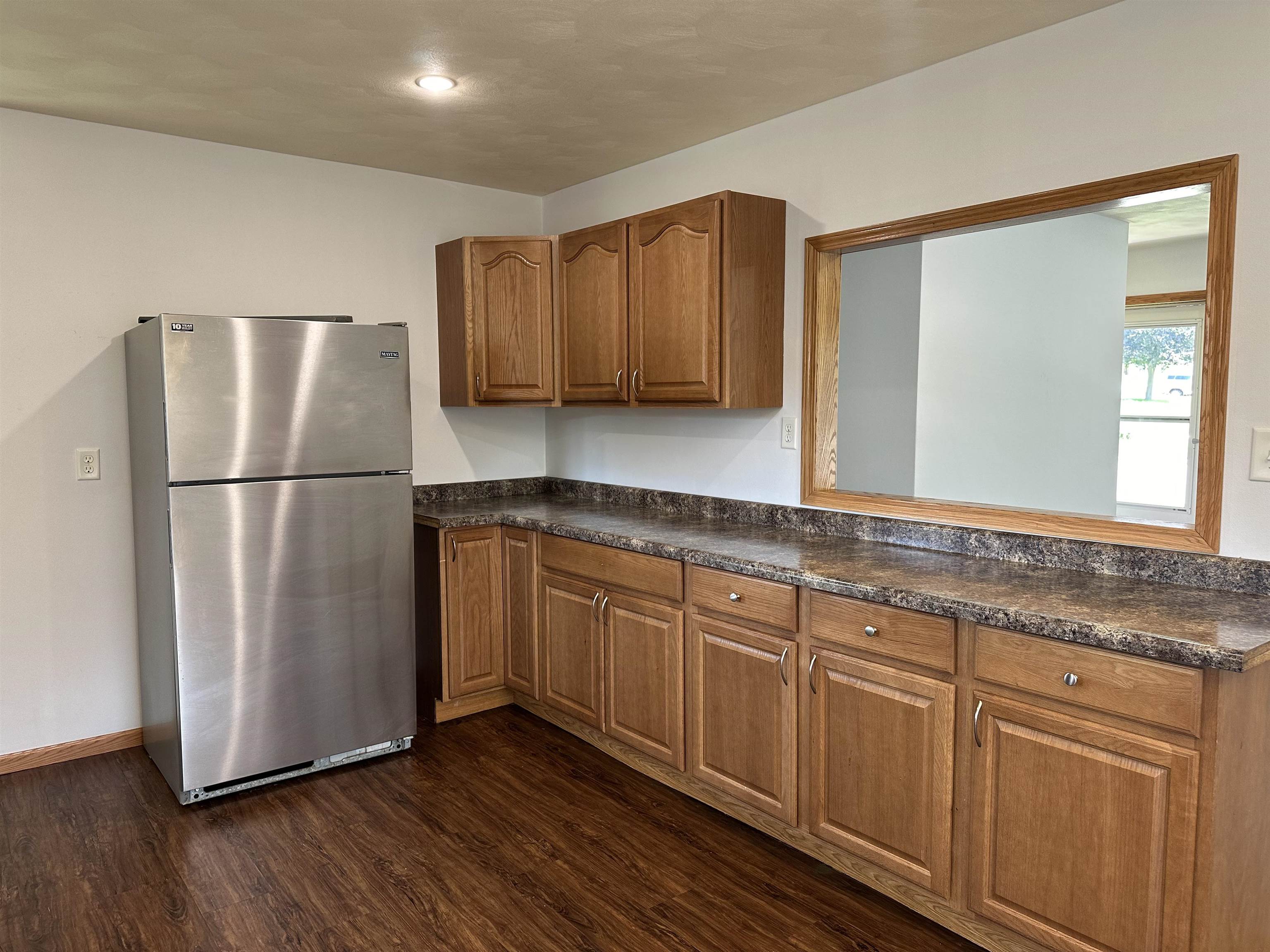 Kitchen with wood cabinets, dark countertops, and a stainless steel refrigerator.