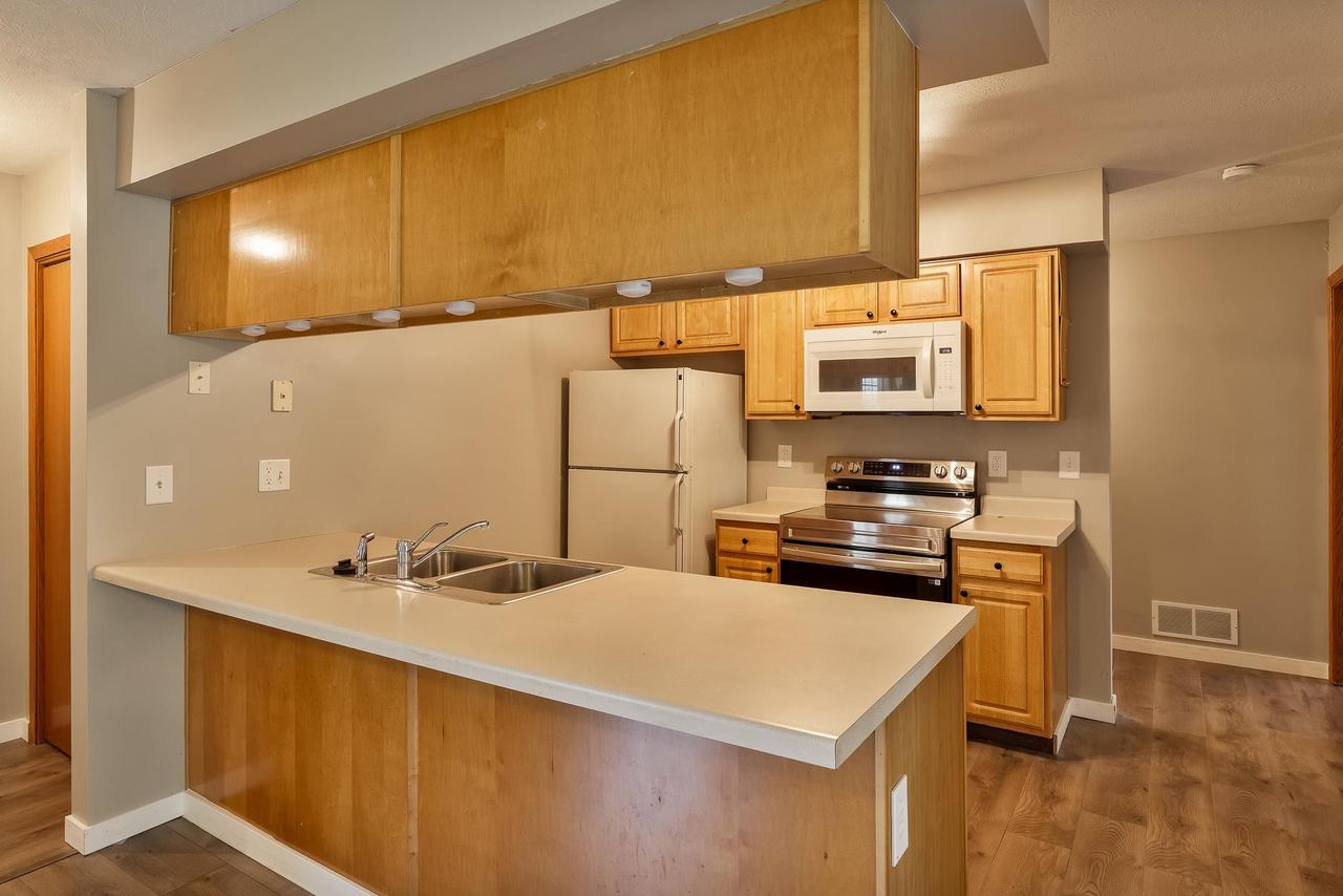 Kitchen with wood cabinets, a large double-sink peninsula, and stainless steel appliances.