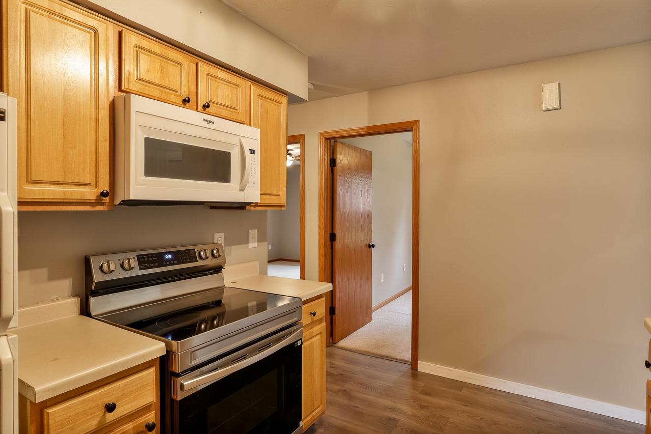 Kitchen with honey-colored wood cabinets, stainless electric range, and over-the-range microwave.