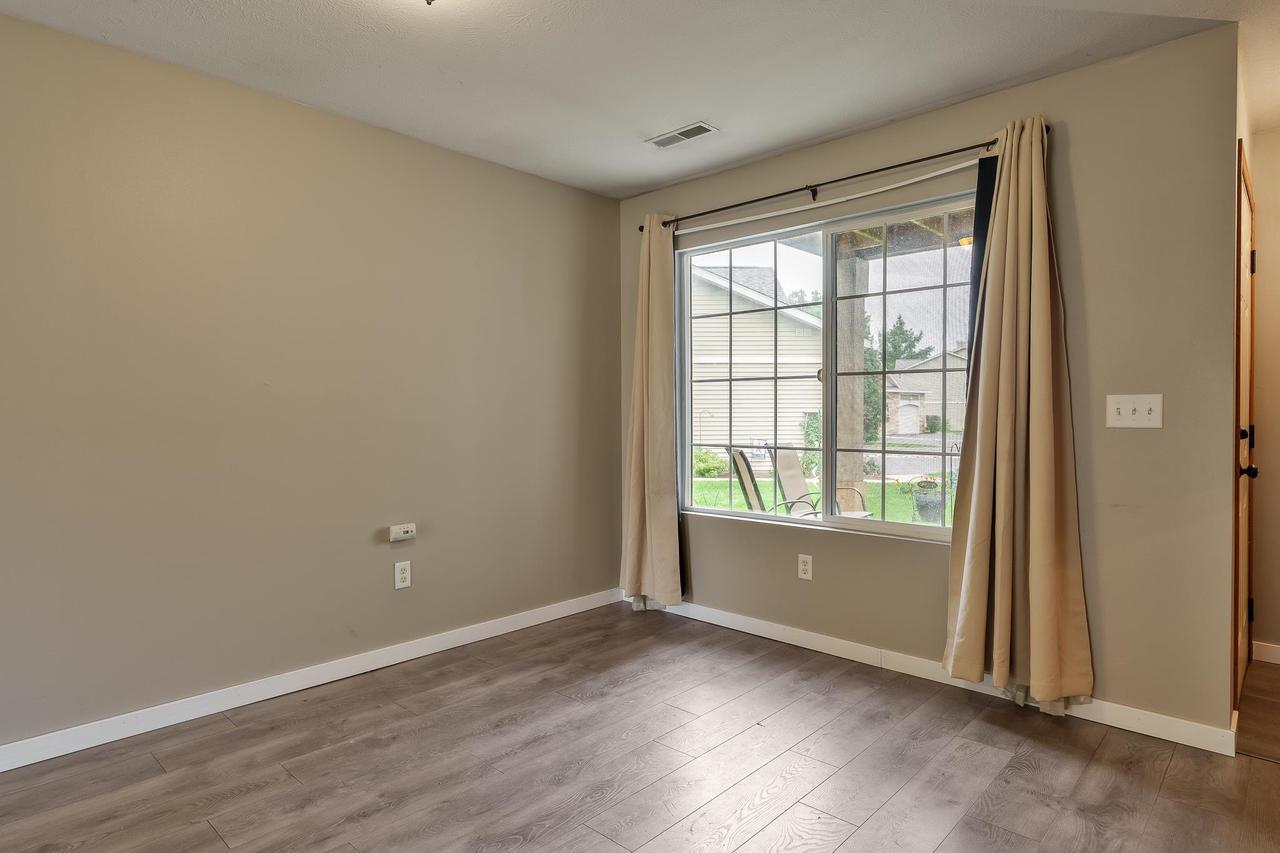 Empty room with plank flooring and a large curtained window overlooking the yard.