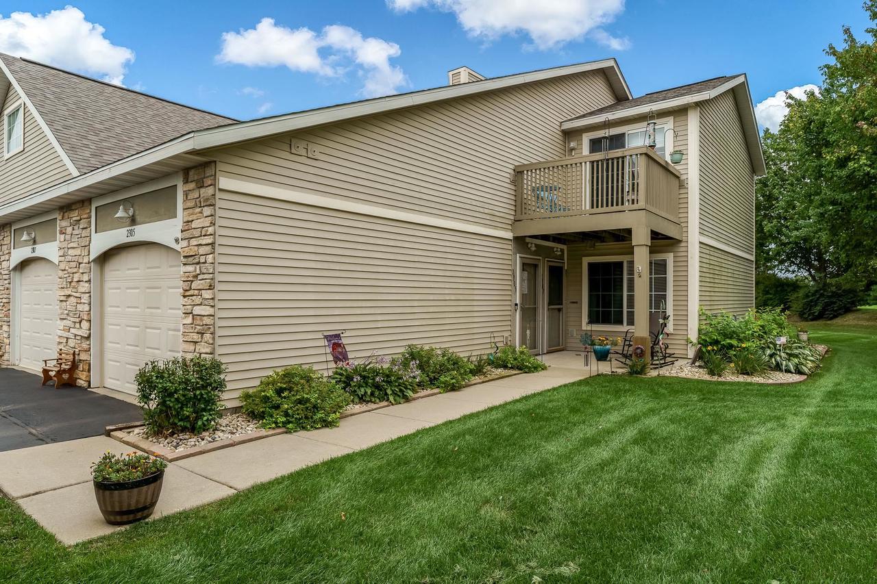 Beige condominium exterior with stone-accented garages and a raised balcony over a covered patio.