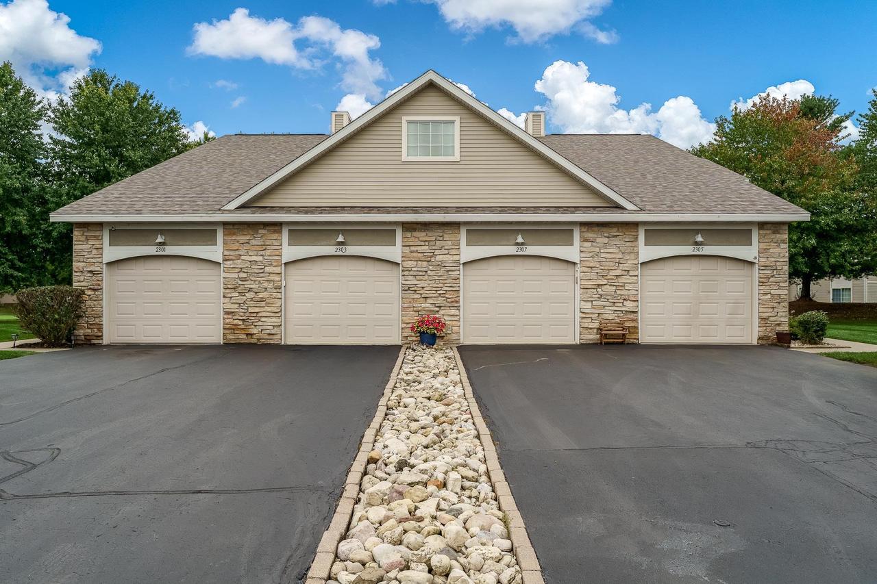 Four-door garage building with stone veneer and a central rock garden.