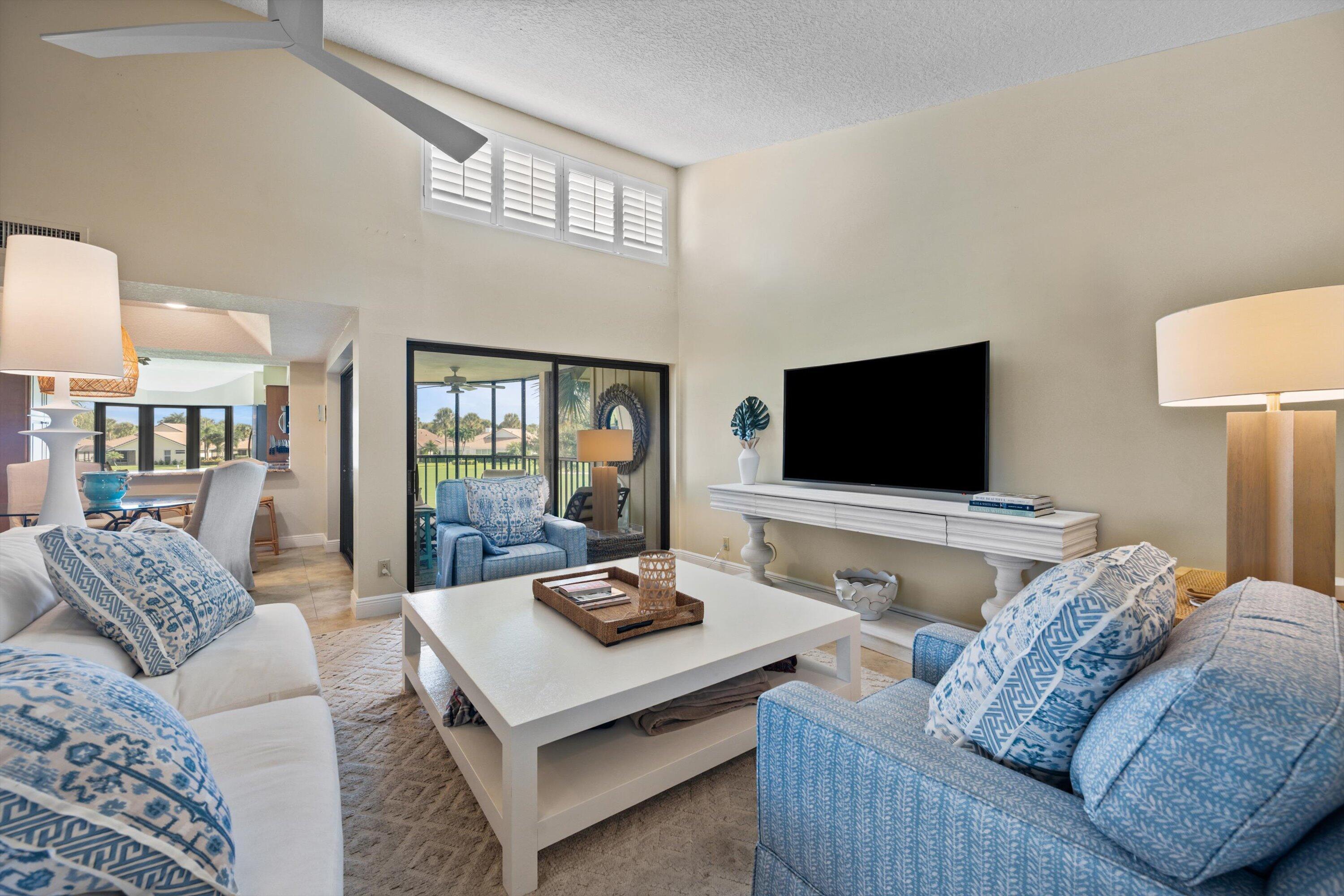 Living room with blue patterned sofas, a vaulted ceiling, and sliding doors to a screened balcony.