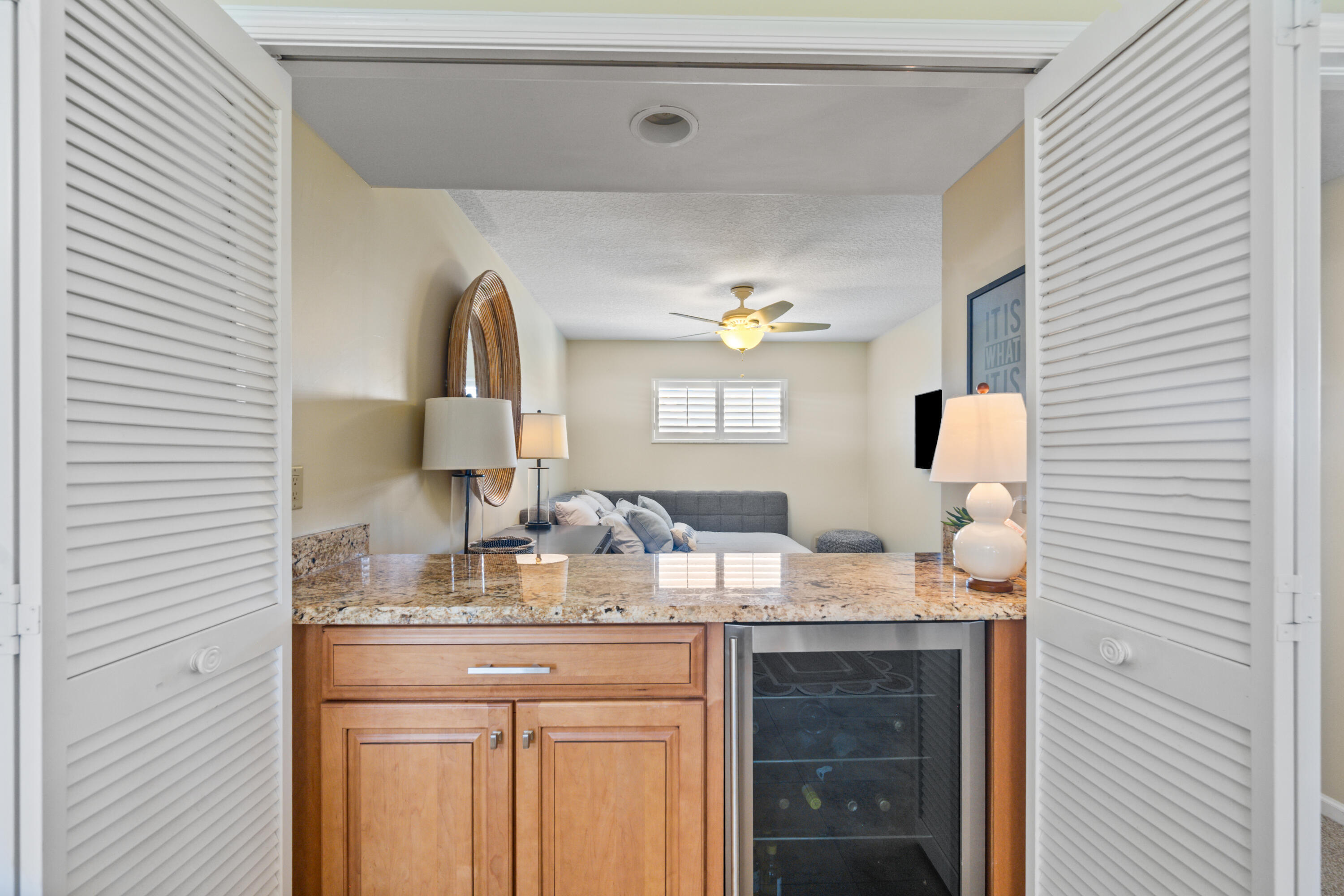 Wet bar with granite counter and wine refrigerator opening onto a furnished living room.