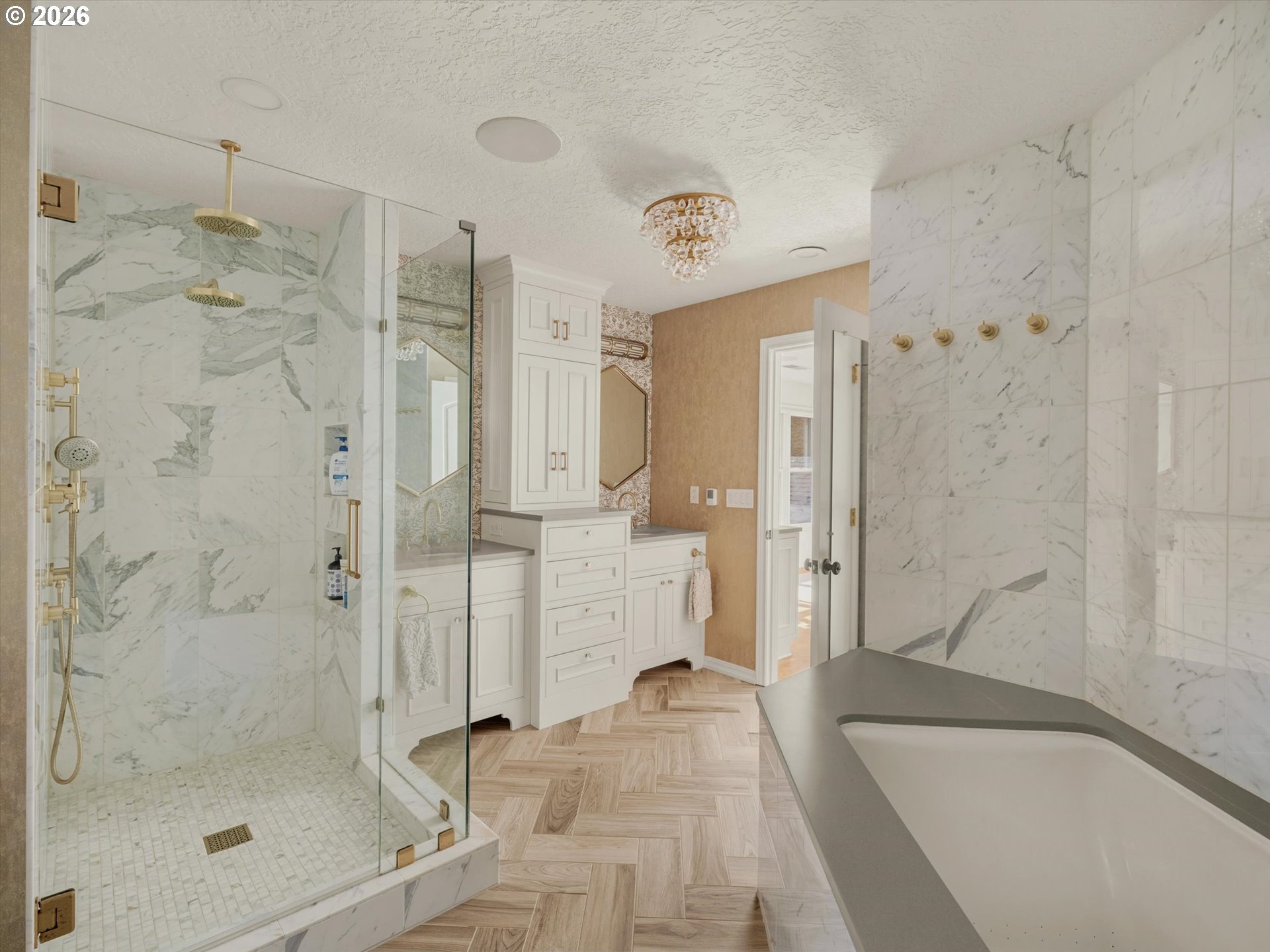 Remodeled bathroom with a glass shower, dual brass showerheads, marble-pattern tile, and a large tub.