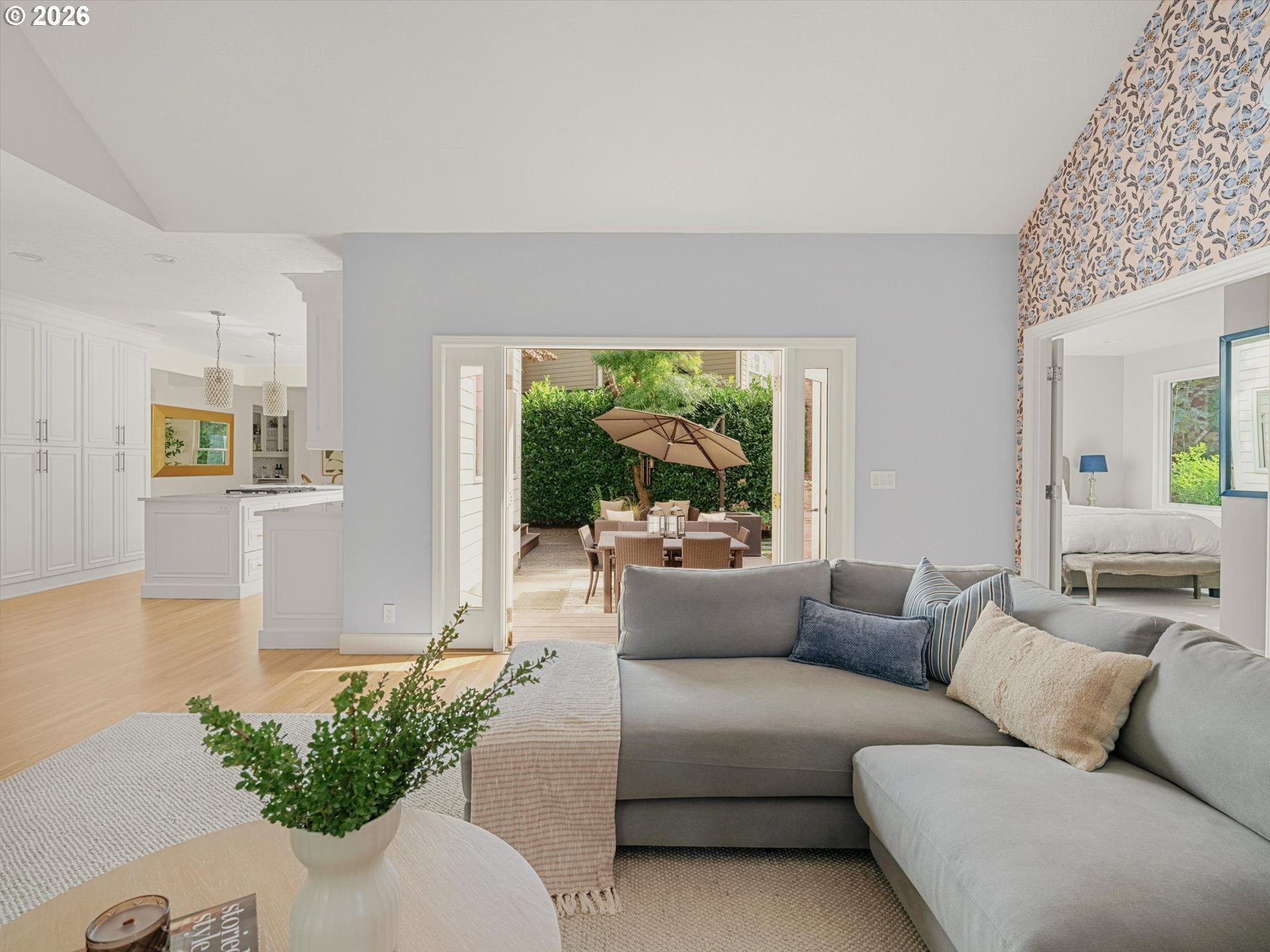 Living room with a gray sectional sofa, opening onto a patio with outdoor dining furniture.