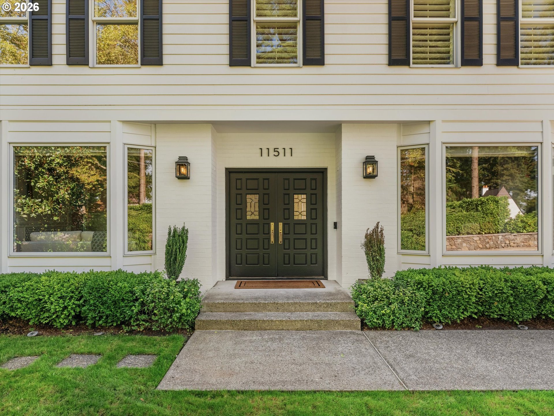 Home entrance with black double doors, brass handles, and 11511 above the doorway.