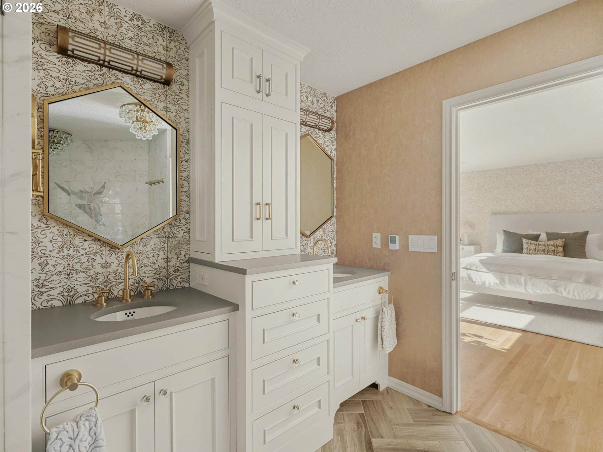 Bathroom vanity with patterned wallpaper, brass fixtures, and a doorway opening to a bright bedroom.