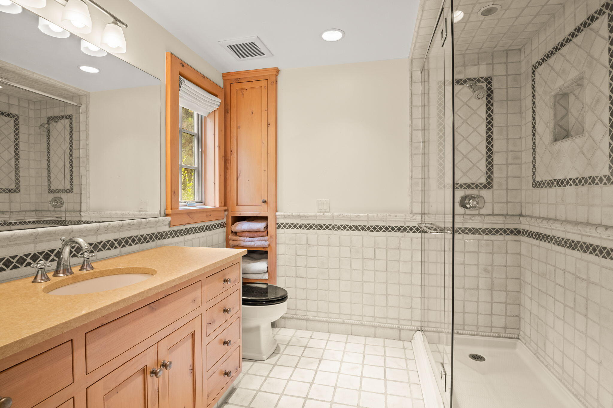 Bathroom with a wood vanity and glass-enclosed tiled shower.
