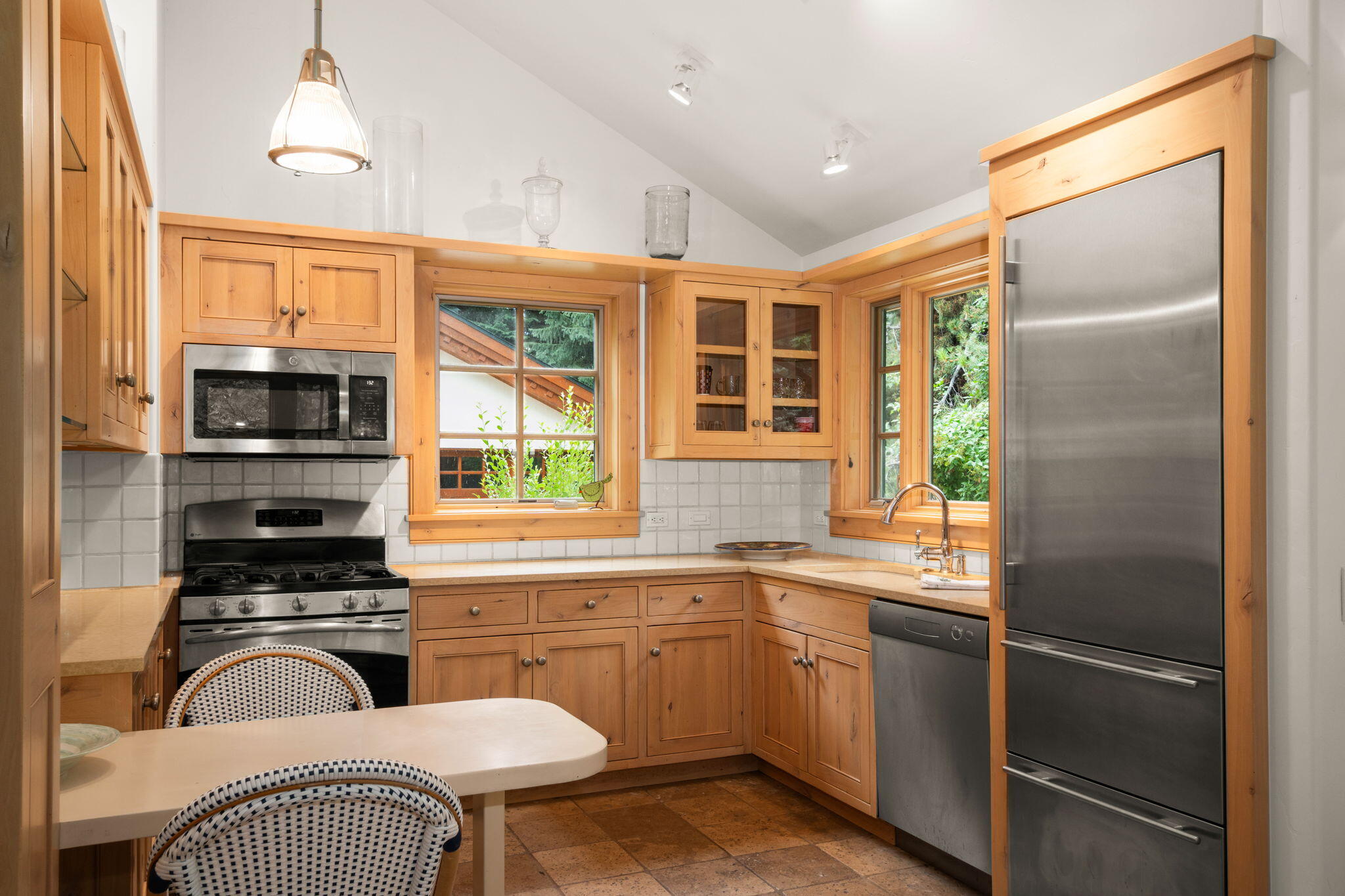Kitchen with warm wood cabinets, stainless steel appliances, and windows overlooking greenery.