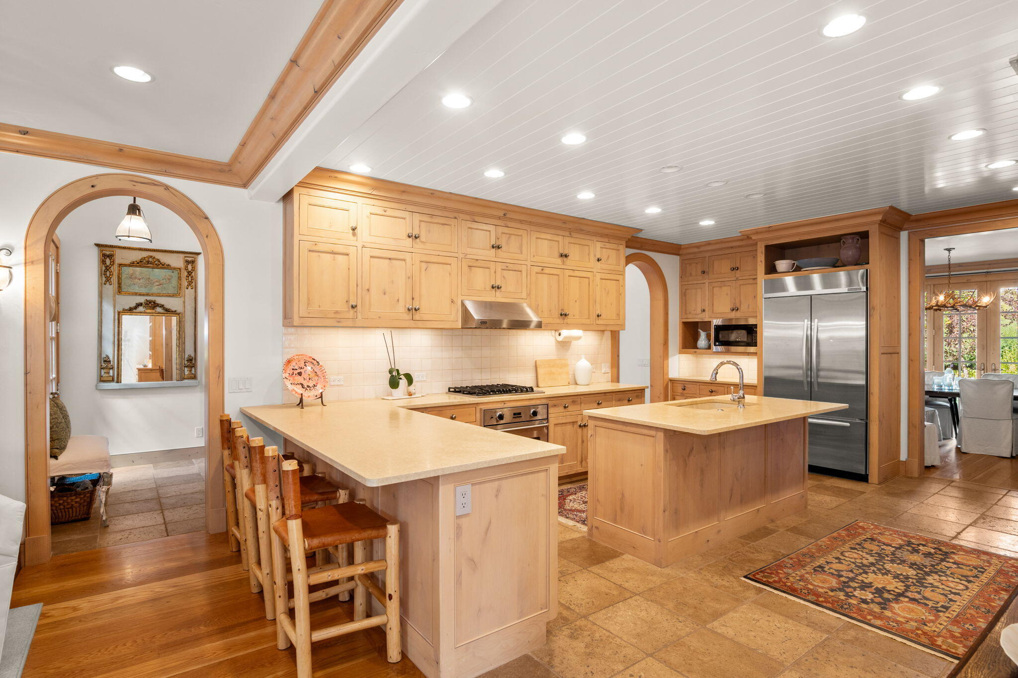 Kitchen with honey-colored wood cabinets, two large islands, bar stools, and stainless steel appliances.