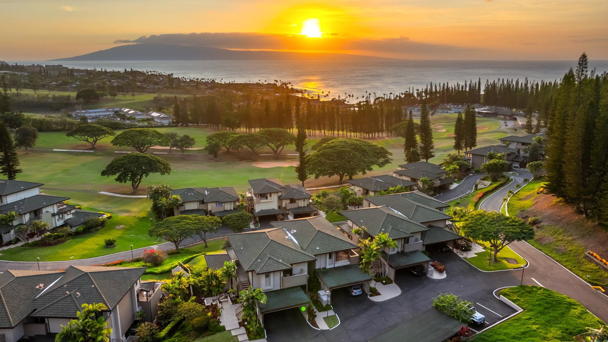Kapalua homes and golf course overlook the ocean and a distant island at sunset.