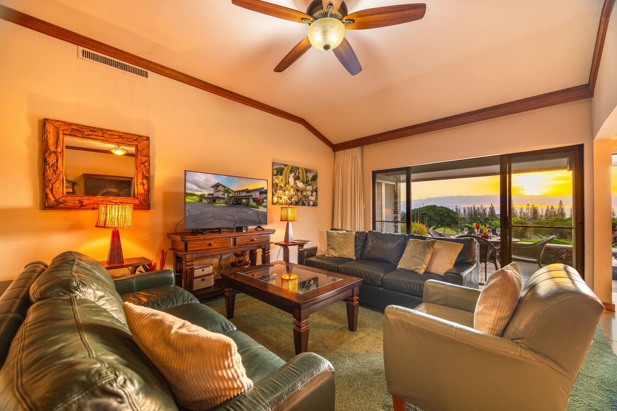 Furnished living room with leather sofas and sliding doors overlooking the ocean at sunset.