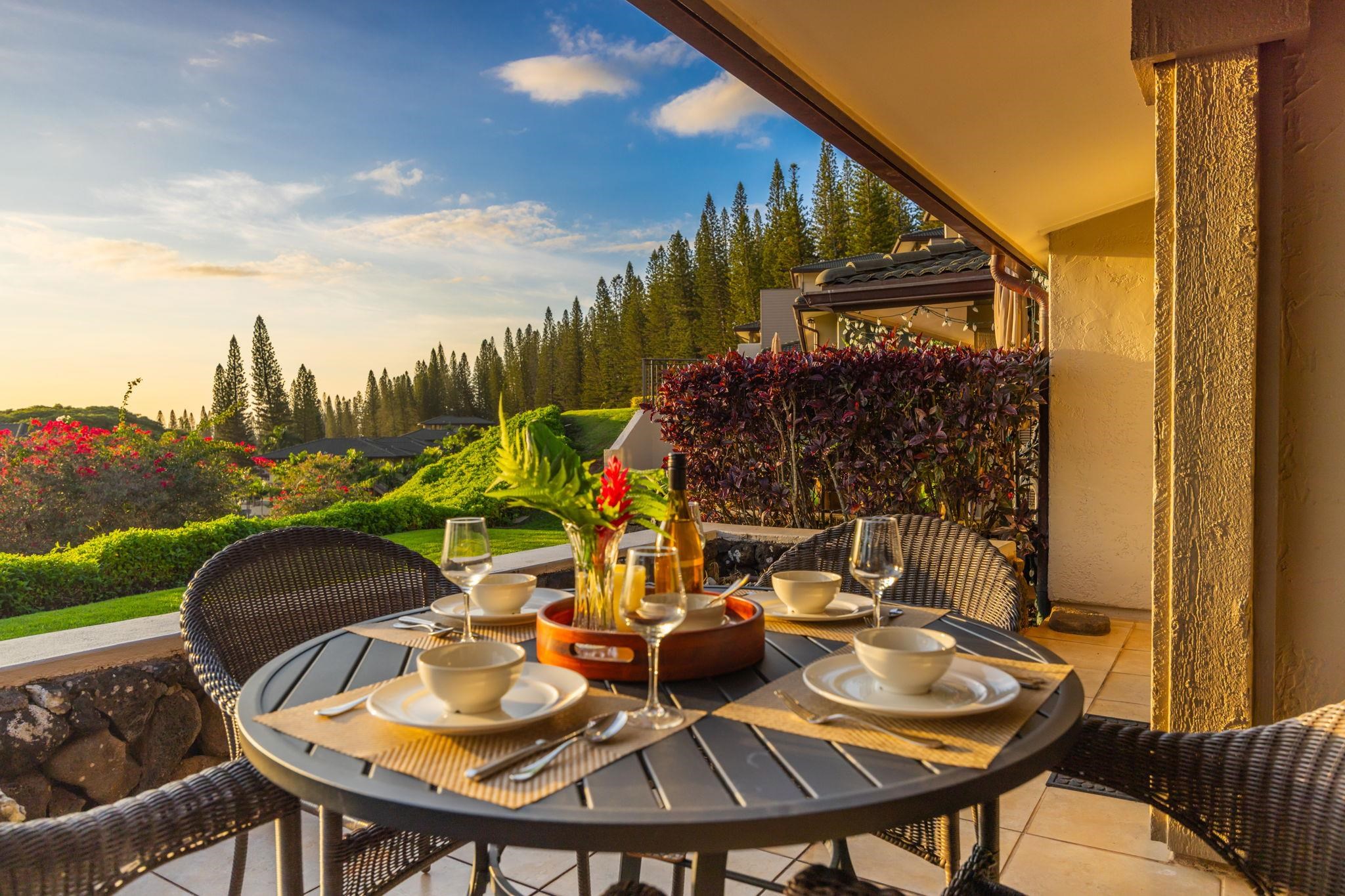 Patio dining table set for a meal, overlooking landscaped gardens and pine trees.