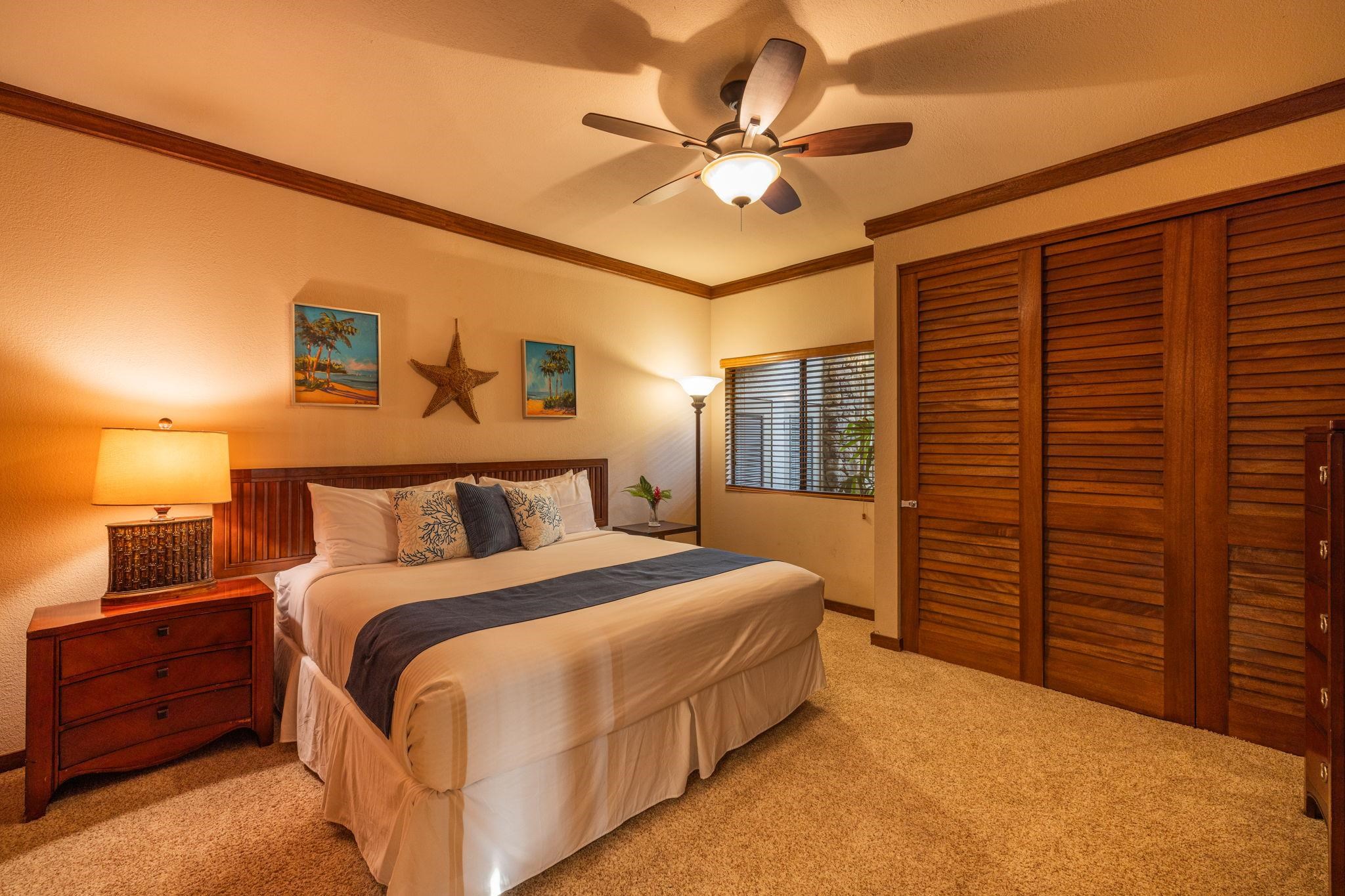 Bedroom with a king bed, dark wood louvered closet doors, and tropical wall art.