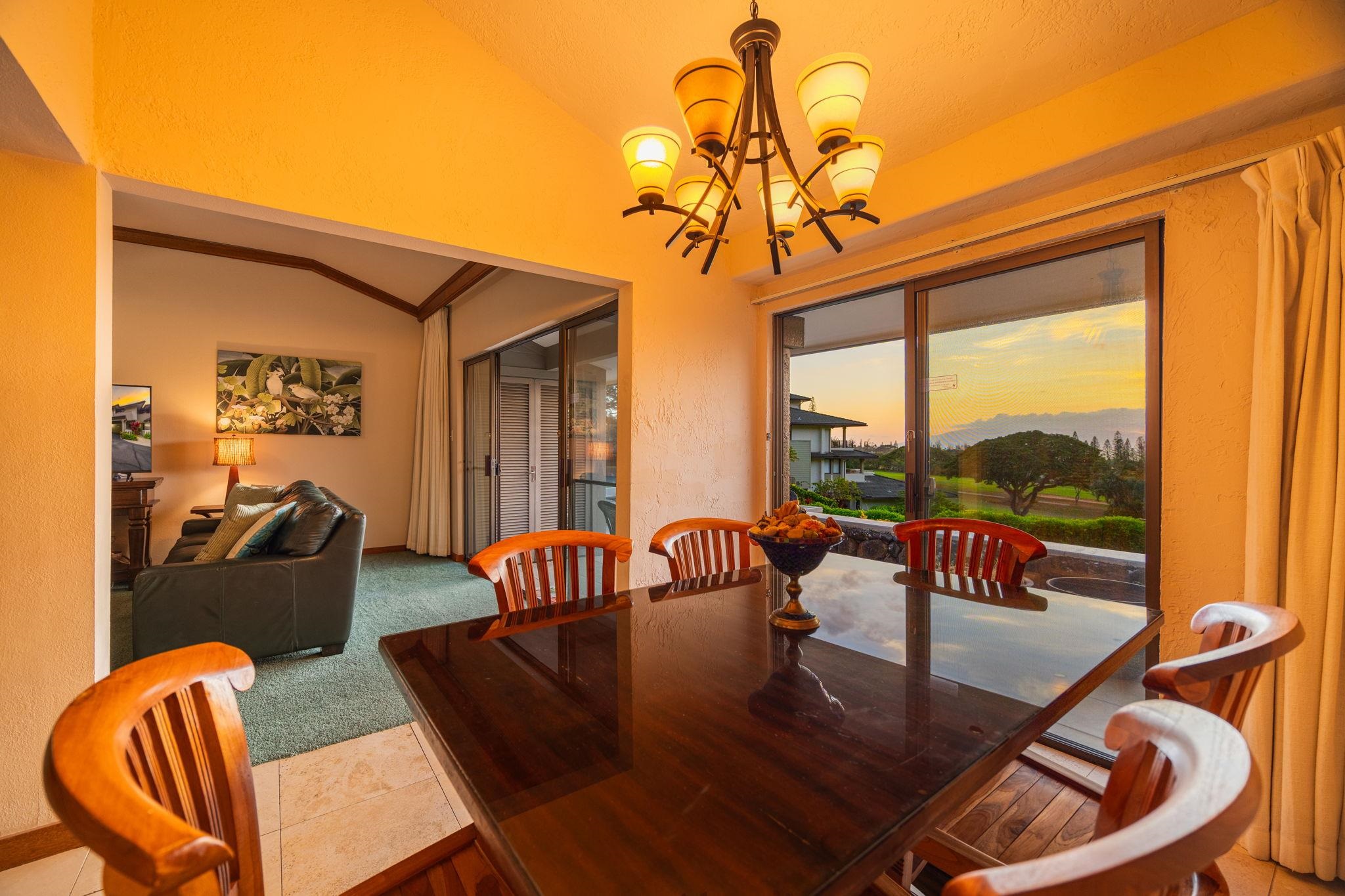 Dining area with a glass-top table and mountain views through sliding doors at sunset.