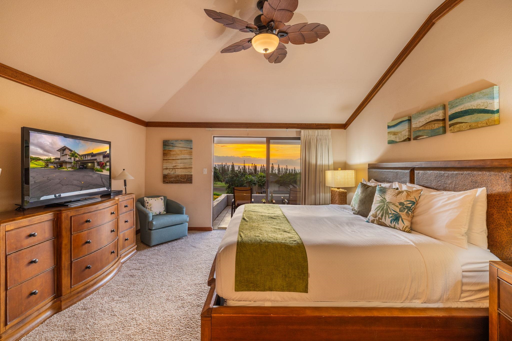 Furnished bedroom with a wooden bed and sliding doors framing an ocean view at sunset.