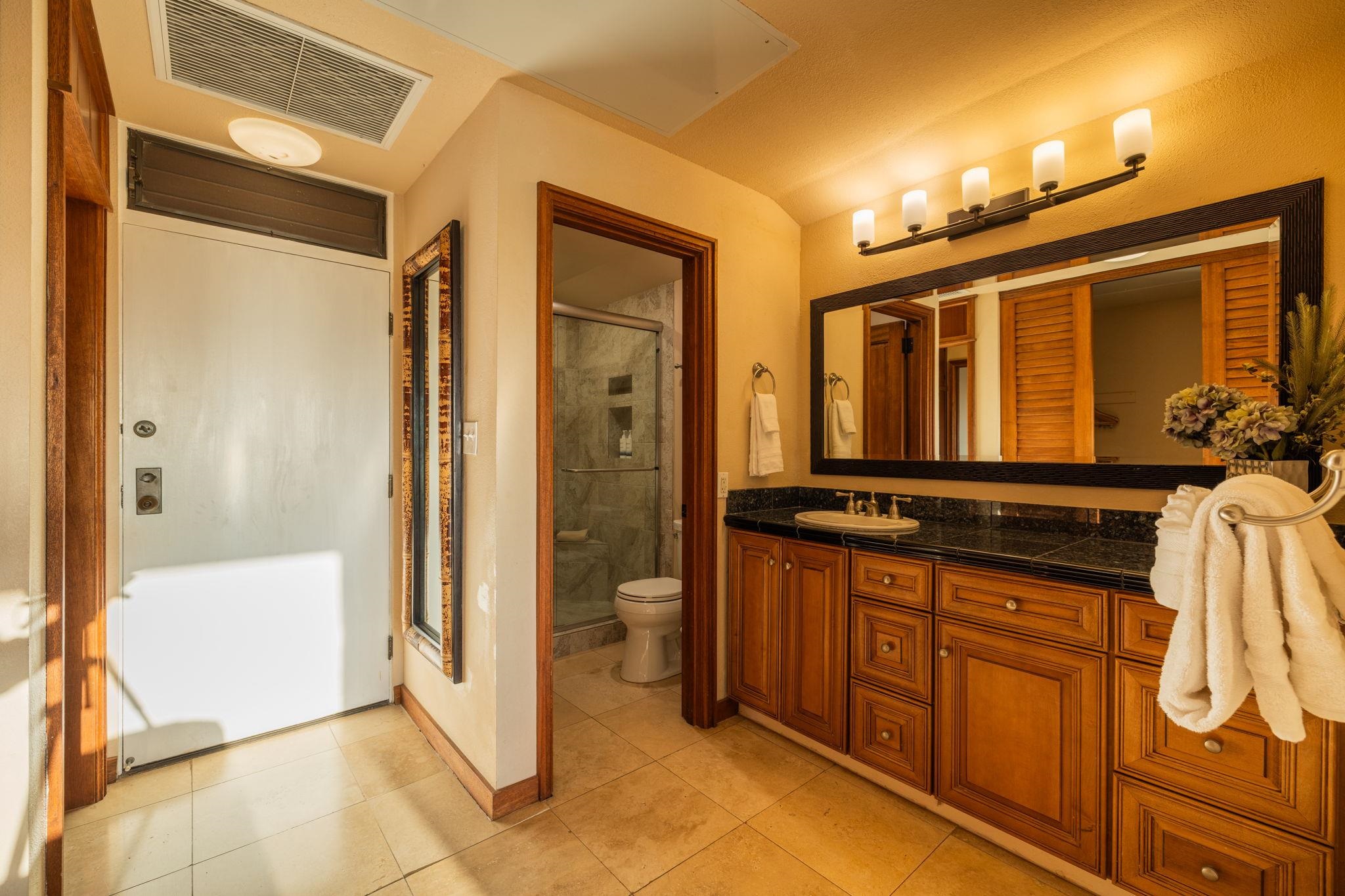 Bathroom with a long wooden vanity and large mirror beside a glass-enclosed shower.