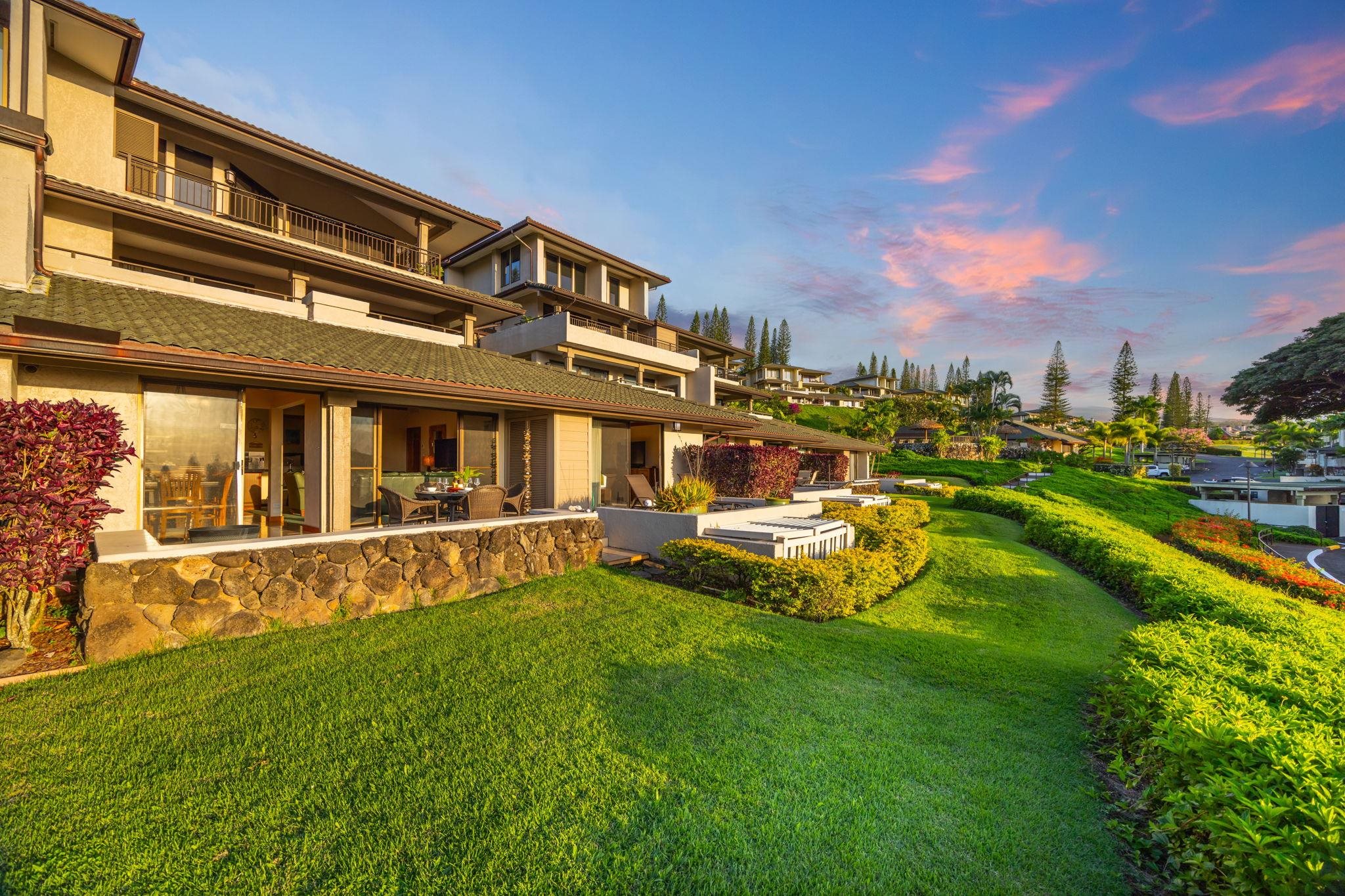 Condominium buildings with furnished patios and tropical landscaping in warm evening light.